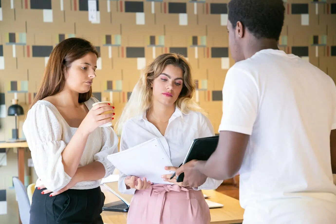 Ein afroamerikanischer Mann zeigt Partnern den Bildschirm eines Tablets.